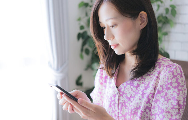 室内でスマートフォンの画面を真剣に見つめ、情報をチェックしている女性